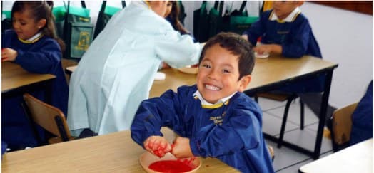 Niño sonriendo mientras come en el comedor del colegio