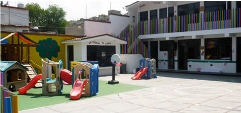Patio del colegio con juegos infantiles, resbaladilla y pasto sintético