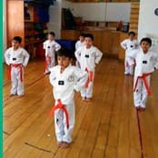 Alumnos entrenando Tae Kwon Do con uniforme y cinta